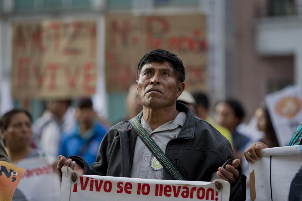 A demonstrator carries a sign that reads in Spanish: "They took them alive, return them alive," in reference to 43 missing students from the Ayotzinapa rural teachers college, during a march to the private TV channel Televisa in Mexico City, Tuesday, March 10, 2015. The missing students' parents and supporters accuse national media outlets of decreasing their coverage of the missing students after statements by then-Attorney General Jesus Murillo Karam who said his investigators indicated all 43 students were killed by the Guerreros Unidos drug gang. The parents still have no concrete information on what happened to their children, and demand their voices be aired in order to continue the search for them. (AP Photo/Eduardo Verdugo)